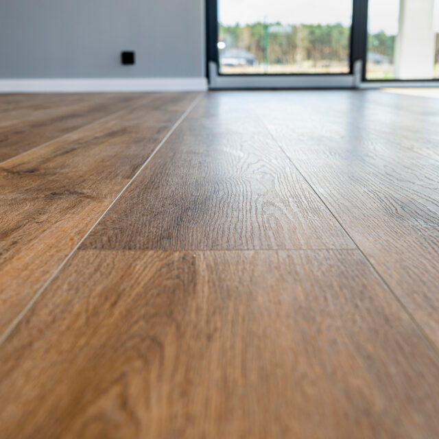 Modern vinyl panels imitating wood in the living room with selective focus and a shadow falling from the window.